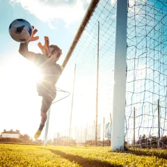 Torwart im Flug nach dem Ball, Fußballplatz auf Sylt im Gegenlicht