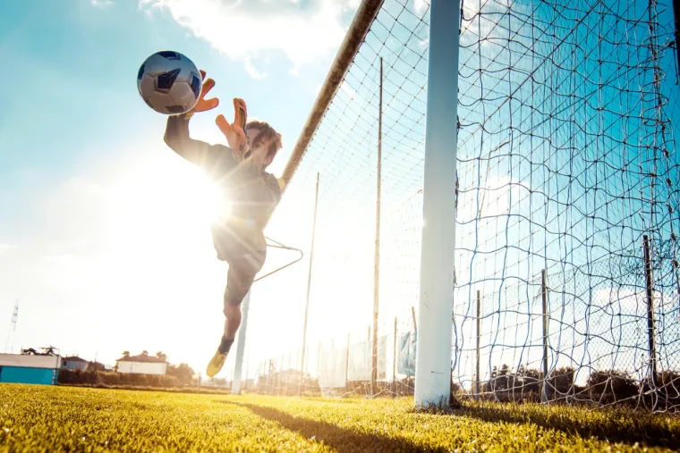 Wer spielt wann? Der neue Sylter Spielplan zeigt alle Fußballtermine der Insel 11 Torwart im Flug nach dem Ball, Fußballplatz auf Sylt im Gegenlicht