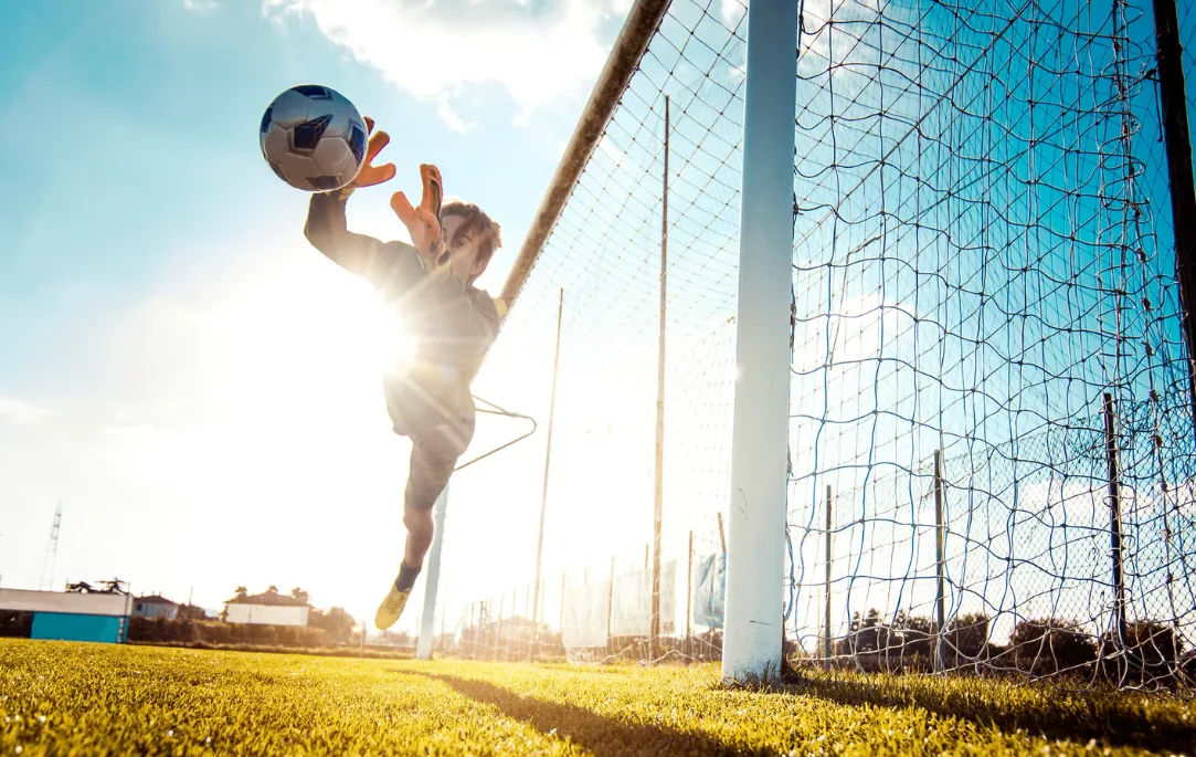 Torwart im Flug nach dem Ball, Fußballplatz auf Sylt im Gegenlicht